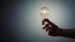 © Tantri - A hand holds an illuminated classic light bulb with a glowing filament against a dark to light gradient background