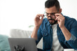 © Prostock-studio - Stressed young Arab man using laptop, having difficulty performing work task, making error at home, copy space. Eastern guy touching glasses, unhappy about his freelance job