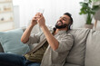 © Prostock-studio - Smiling young Arab guy in headphones listening to music or audio book on couch at home. Happy Eastern man relaxing to favorite song, enjoying popular playlist indoors. Weekend pastimes concept