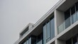 © firma - Modern architectural details of a contemporary building with balconies and large windows under an overcast sky.