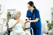 © Nuttapong punna - Young nurse helping elderly woman walk in the room, holding his hand, supporting. Treatment and rehabilitation after injury in assisted living facility, senior care