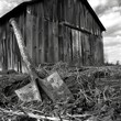 © Justlight - A rusty hand plow leaning against a decaying barn showing signs of once being a vital tool for tilling the land. Black and white art