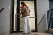 © dtatiana - Woman unlocking entrance door of apartment building at night. Returning home after day out.