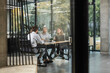 © ty - Business people in the office behind a glass partition in casual clothes, with blurred bokeh background.