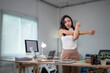© Wasana - Office worker stretching arms at her desk in the office