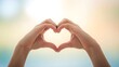 © sea sae - Hands forming a heart shape with fingers against a soft, bokeh background
