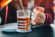 © EdNurg - Person pouring steaming tea from a French press into a glass mug, cozy morning moment with visible hand, steam and warm tabletop detail