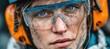 © rifai_art - Intense portrait of a grimy worker wearing clear safety goggles and orange ear protection, looking straight ahead
