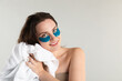 © New Africa - Beautiful woman wearing eye patches drying hair with towel on light grey background. Space for text