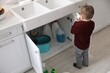 © New Africa - Child safety at home. Little boy playing with cleaning products in kitchen