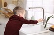 © New Africa - Child safety at home. Little boy opening faucet at sink in kitchen