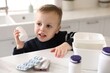 © New Africa - Child safety at home. Little boy playing with pills at table in kitchen