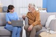 © New Africa - Care worker teaching senior man to use laptop at retirement home