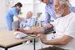© New Africa - Caregiver measuring senior man's blood pressure at home, closeup