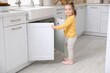 © New Africa - Child safety at home. Little girl opening cabinet under sink in kitchen