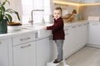 © New Africa - Child safety at home. Little boy on stool at sink in kitchen