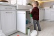 © New Africa - Child safety at home. Little boy playing with cleaning products in kitchen
