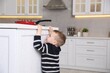 © New Africa - Child safety at home. Little boy reaching for hot frying pan in kitchen, space for text