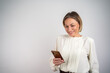 © Nenad - Mixed race businesswoman using smartphone isolated on grey wall