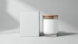 © Amanda - Minimalist candle mockup, white glass jar with wooden lid next to a blank square cardboard box, clean studio photography with soft shadows.