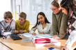 © BalanceFormCreative - A small group of students is in their elementary classroom while a mixed-race teacher guides them through a math and geometry lesson. She is asking questions and helping them stay focused as they work