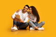 © Prostock-studio - Happy Young Middle Eastern Couple Using Digital Tablet While Sitting Over Yellow Background In Studio, Cheerful Arabic Man Amd Woman Shopping Online, Browsing Internet Or Watching Videos, Free Space