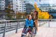 © unai - Caregiver pushing adult man in wheelchair in city