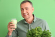 © Pixel-Shot - Mature man with glass of vegetable smoothie and parsley on green background, closeup