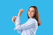 © Pixel-Shot - Pretty young woman rolling up her sleeve on light blue background