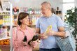 © JackF - Couple of elderly man and elderly woman choosing olive or sunflower oil in bottle in grocery store