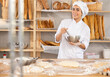 © JackF - Young female baker in uniform whisking dough in bowl