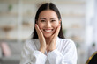 © Prostock-studio - Closeup of asian woman in white bathrobe touching her skin and smiling, enjoying her young smooth skin, copy space. Cheerful young chinese lady touching her cheeks with both hands, home interior