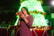 © Djavan Rodriguez - Young latina woman frowning while checking smartphone at park holiday event
