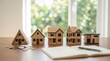 © Meow Creations - Row of wooden house models on desk with coins and notebook for real estate investment planning