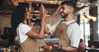 © AzeemudDeen25/peopleimages.com - Waiter, high five and people with tablet in coffee shop for barista training, counting stock or inventory management. Hospitality industry, excited and digital tech for cafe system or order success