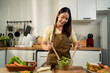 © Kawee - Asian young woman cooking healthy foods in kitchen in morning at home.