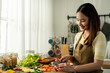 © Kawee - Asian young woman cooking healthy foods in kitchen in morning at home.