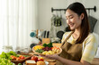 © Kawee - Asian young woman cooking healthy foods in kitchen in morning at home.