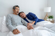© Kawee - Asian elderly older male gay couple sitting on bed in bedroom at home.