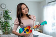 © Kawee - Asian beautiful woman standing alone and playing an ukulele in house.