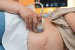 © CatalnIlie - Pregnant woman getting an abdominal ultrasound scan detecting fetal heartbeat and monitoring prenatal health