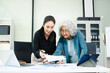 © Nuttapong punna - Asian businesswomen reviewing documents in modern office. Mentoring, consulting and teamwork concept with laptop and tablet. Corporate collaboration