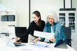 © Nuttapong punna - Asian businesswomen reviewing documents in modern office. Mentoring, consulting and teamwork concept with laptop and tablet. Corporate collaboration