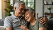 © justsann - Happy elderly Asian couple embracing and smiling warmly on a couch.