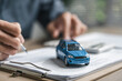 © Garun Studios - Car purchase concept with contract signing, showing vehicle agreement, insurance coverage, auto loan planning, and financial responsibility during dealership buying and ownership transfer.