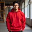 © Gah - A handsome man in a vibrant red hoodie stands in an urban interior with blurred background lights and windows