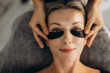 © Roman - Woman getting eyelash extension procedure with eye patches