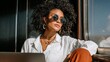 © Julia - An attractive Black female enjoys freelance work on a yacht, using her laptop while sailing, capturing the remote‑work vacation and digital nomad lifestyle with a smile toward the camera