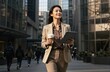 © utaem2022 - Confident businesswoman walking city street holding tablet and coffee