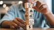 © AR Creations - A person carefully stacking wooden blocks representing business concepts like ideas, analysis, goals, processes, partnership, and finance.